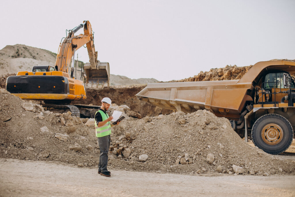Imagen de una escavacion con un trabajador mirando papeles